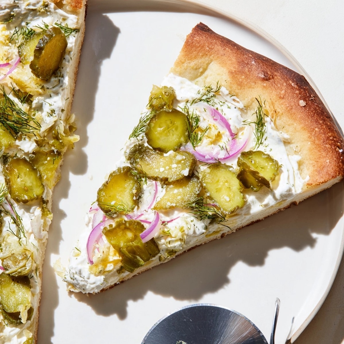 Close-up of a freshly baked Pickle Pizza, golden crust, creamy sauce, and tangy pickles.