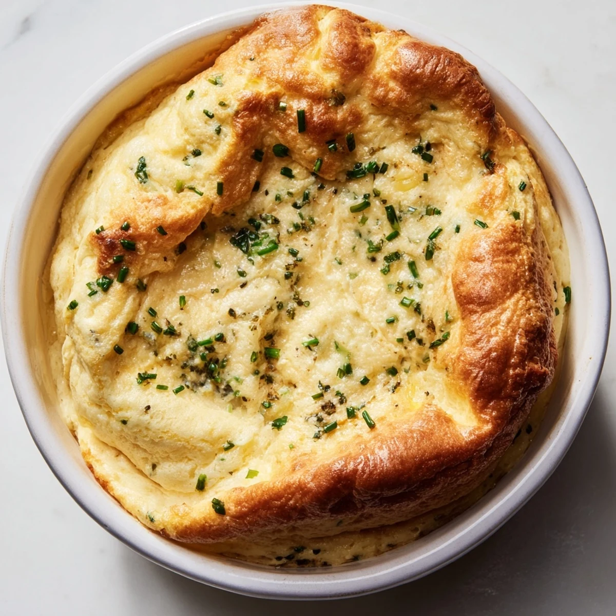 Warm, freshly baked Savory Cheese and Herb Soufflé, with herbs poking out, ready to serve.
