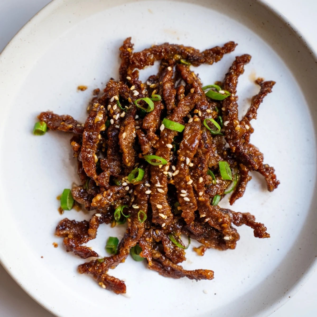 Golden-brown Beef Crispy glistening with a savory sauce, beautifully garnished with green onions.