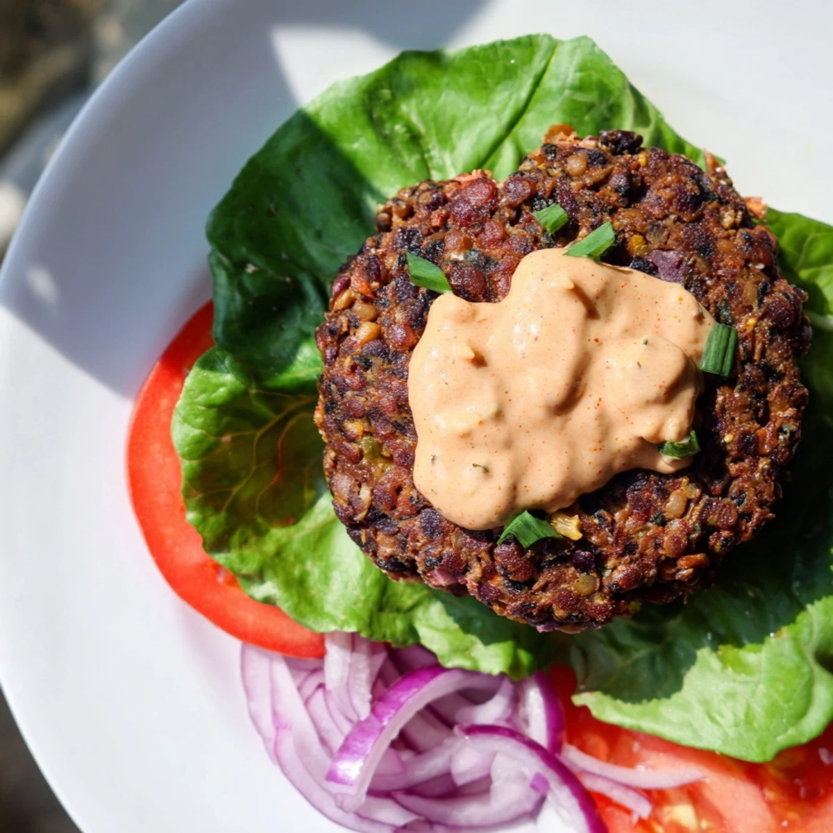 Close-up of a juicy Vegan Black Bean Burger with smoky chipotle mayo, ready to eat.