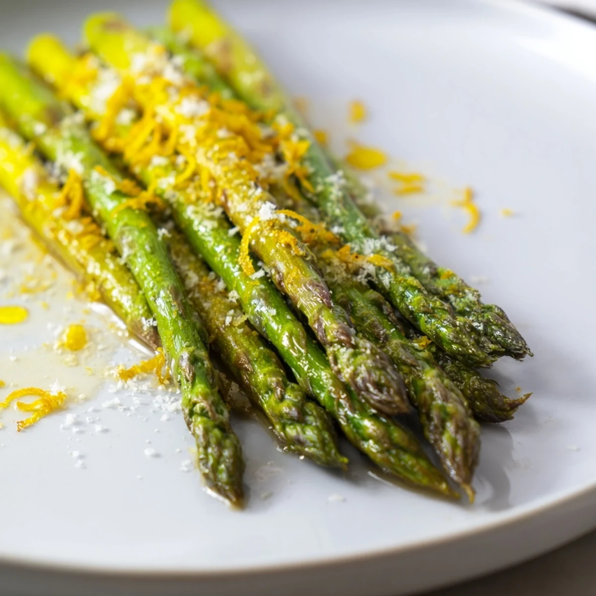 Fresh, tender Roasted Asparagus with Parmesan and lemon, offering bright flavors on a white plate.
