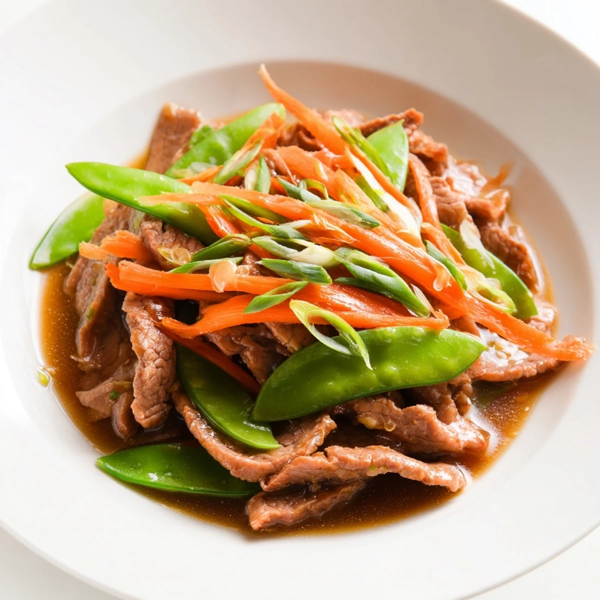 Close-up view of a flavorful Beef Stir Fry with snow peas, served in a bowl, steam rising.