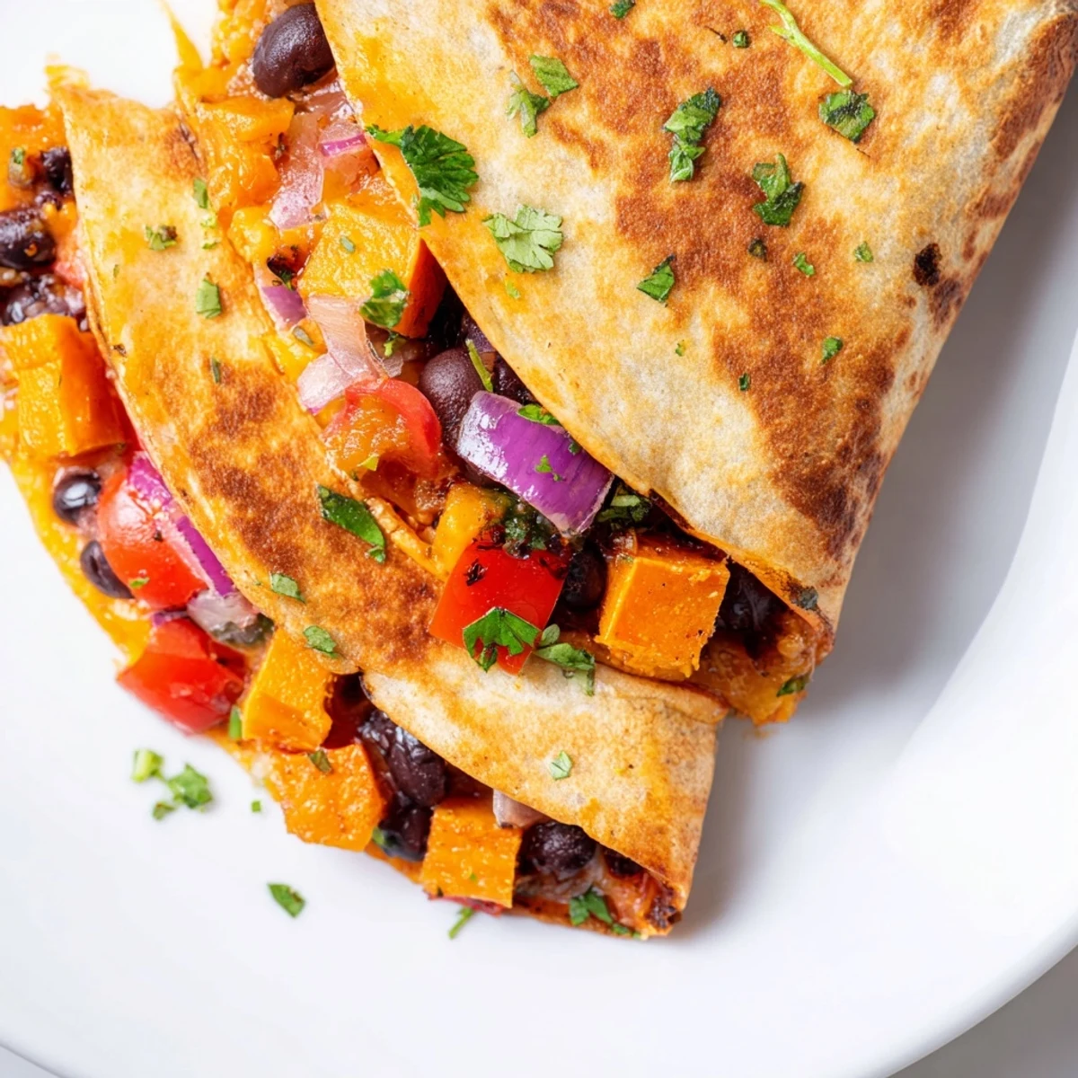 Freshly cut wedges of Roasted Sweet Potato and Black Bean Quesadillas are plated with a side of creamy guacamole and a bright bowl of salsa.