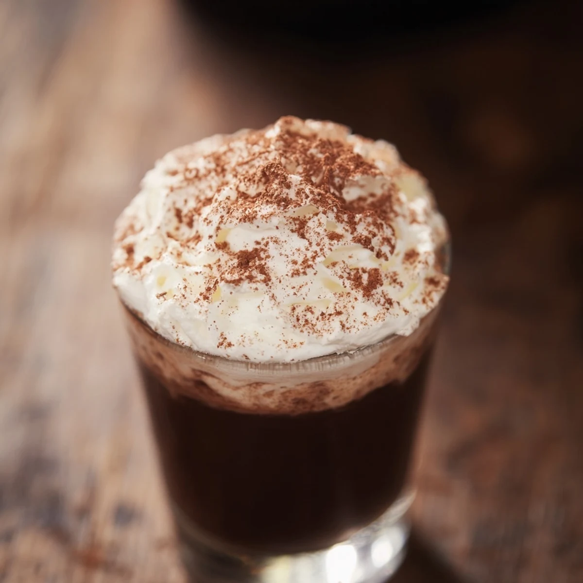 Four shot glasses of Chocolate Shot with Cream feature a rich chocolate liqueur base and a fluffy whipped cream topping, garnished with grated chocolate for an indulgent after-dinner treat.