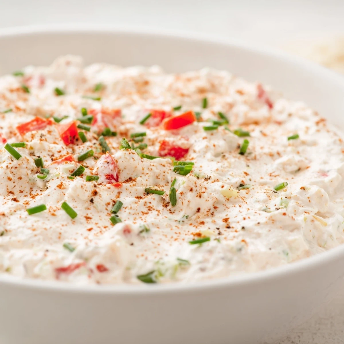 The best Creamy Appetizer Dip served chilled in a ceramic bowl, perfect for parties with gluten-free crackers and crunchy carrot sticks.