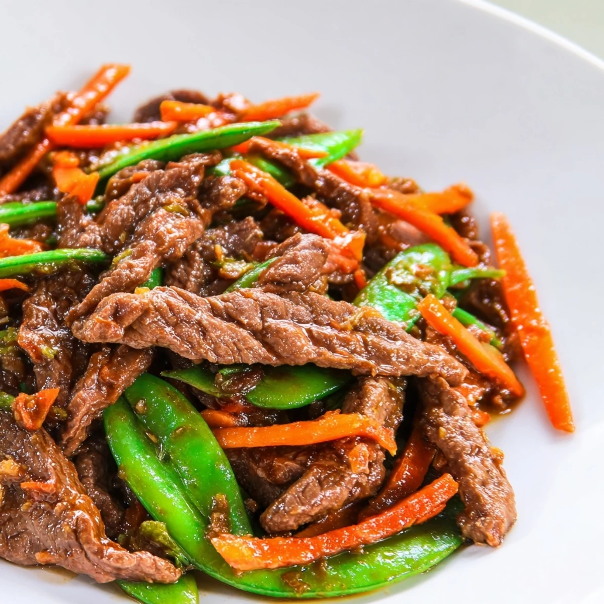 This quick Beef Stir Fry with Snow Peas and Carrots is served steaming hot over a bowl of fluffy white rice.