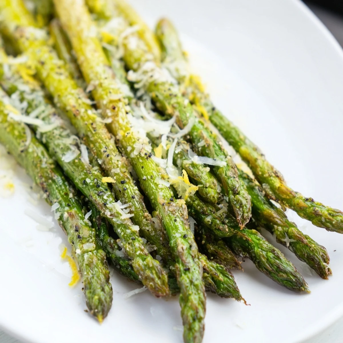 Close-up of Roasted Asparagus with Parmesan and Lemon, showing melted cheese and fresh lemon zest over crisp green stalks.