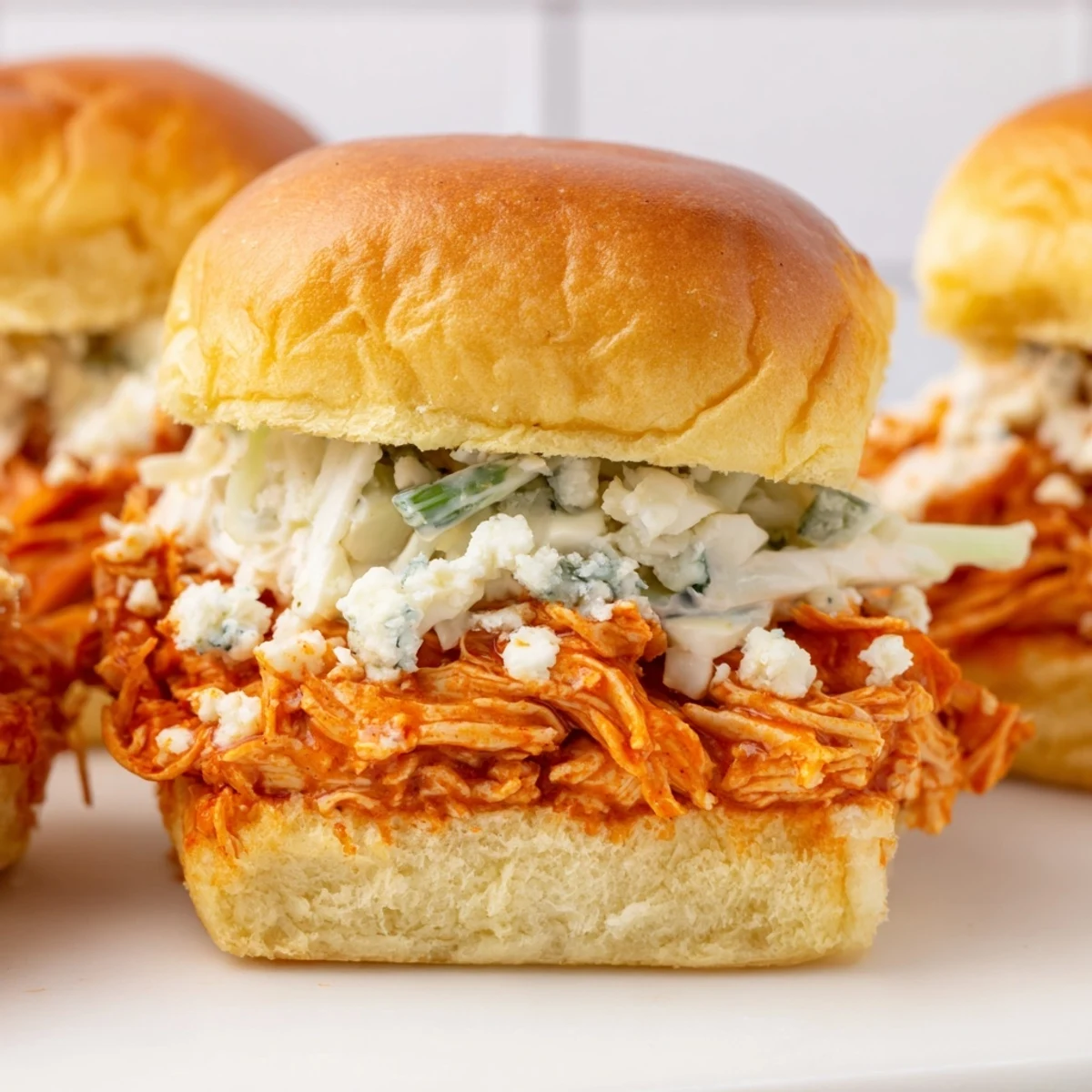 Freshly baked Super Bowl Buffalo Chicken Sliders brushed with butter, served with celery sticks and extra ranch for dipping.