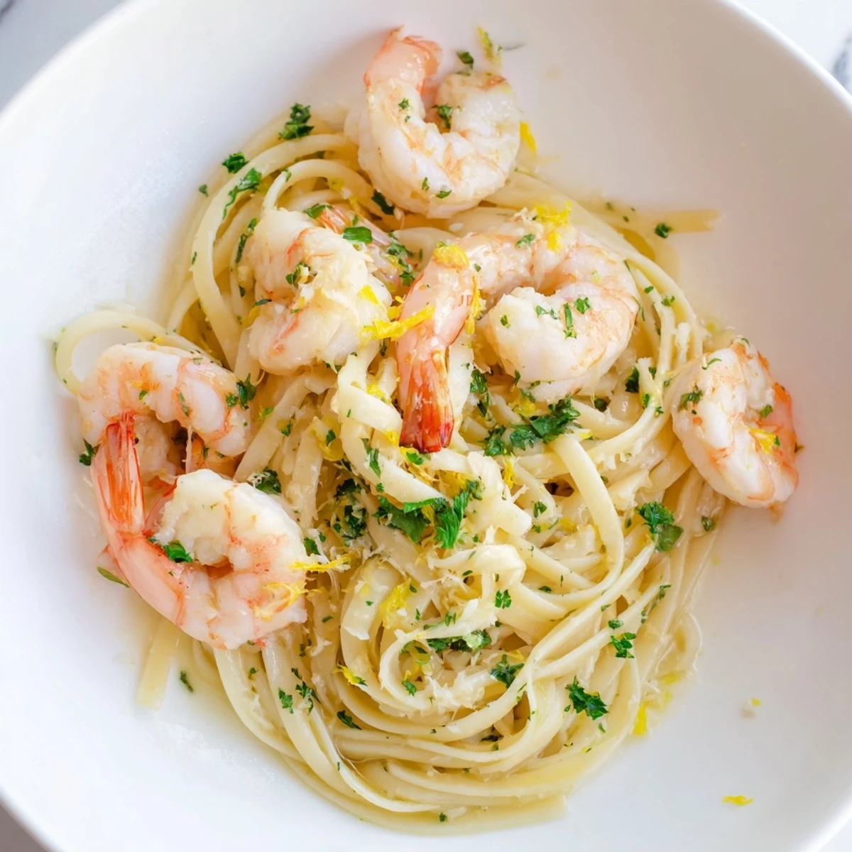 A skillet of sizzling Lemon Shrimp Pasta with Garlic, garnished with chopped parsley and lemon wedges for a zesty, garlicky main course.