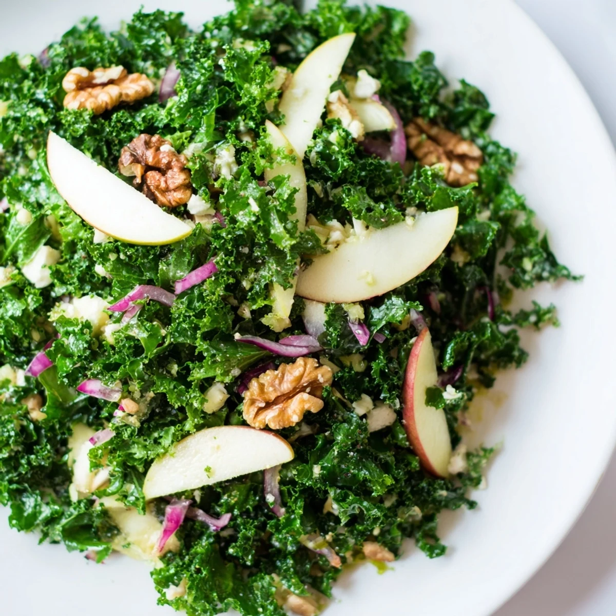 A close-up of vibrant Green Kale and Apple Salad with Walnuts, featuring crisp apple slices and toasted walnuts on a wooden table.  