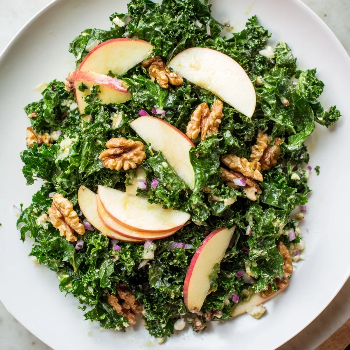 Fresh Green Kale and Apple Salad with Walnuts tossed in a shiny maple-Dijon dressing, topped with crumbled feta and cranberries.  