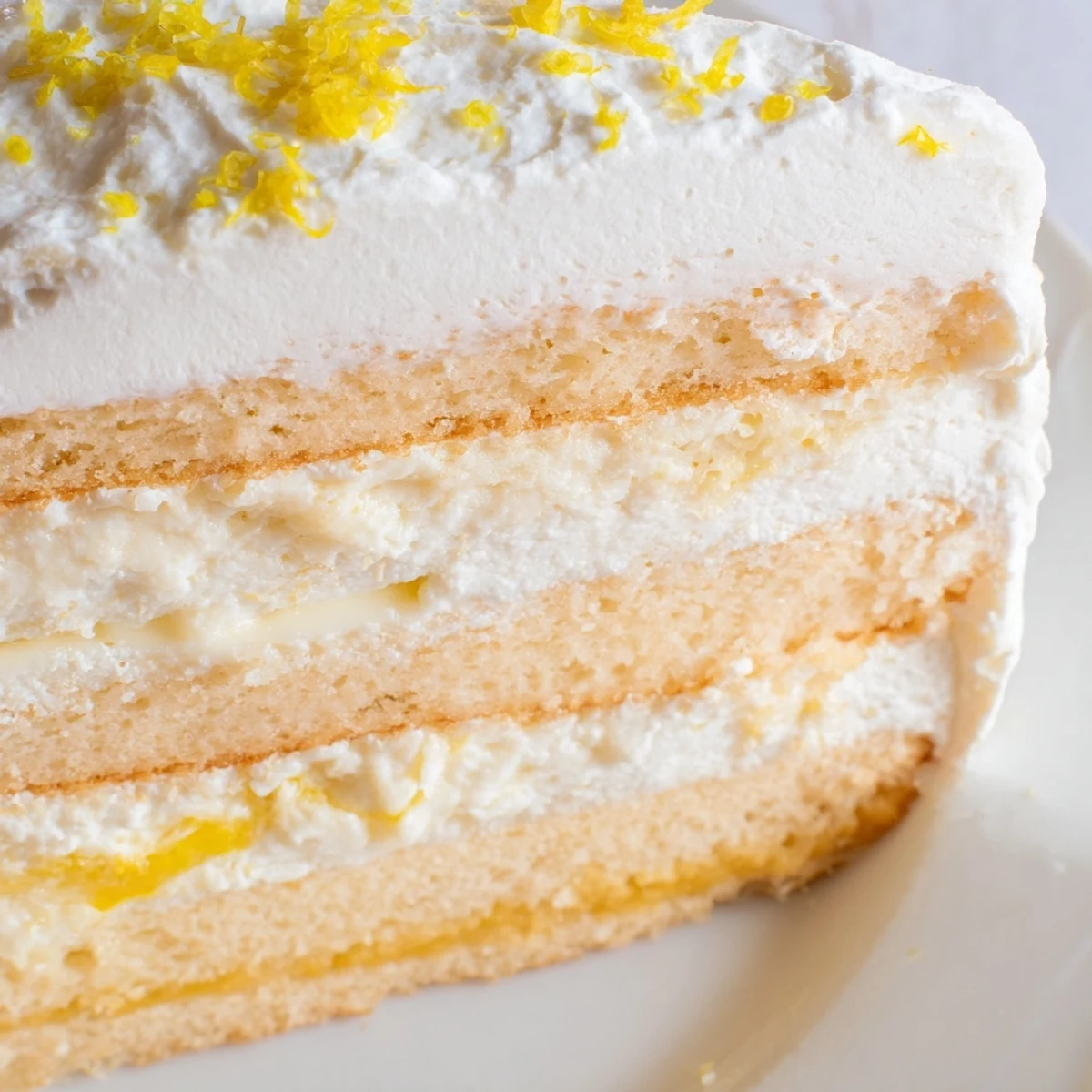 Freshly baked Limoncello Mascarpone Cake layers show sponge soaked in syrup with creamy filling and lemon zest garnish.