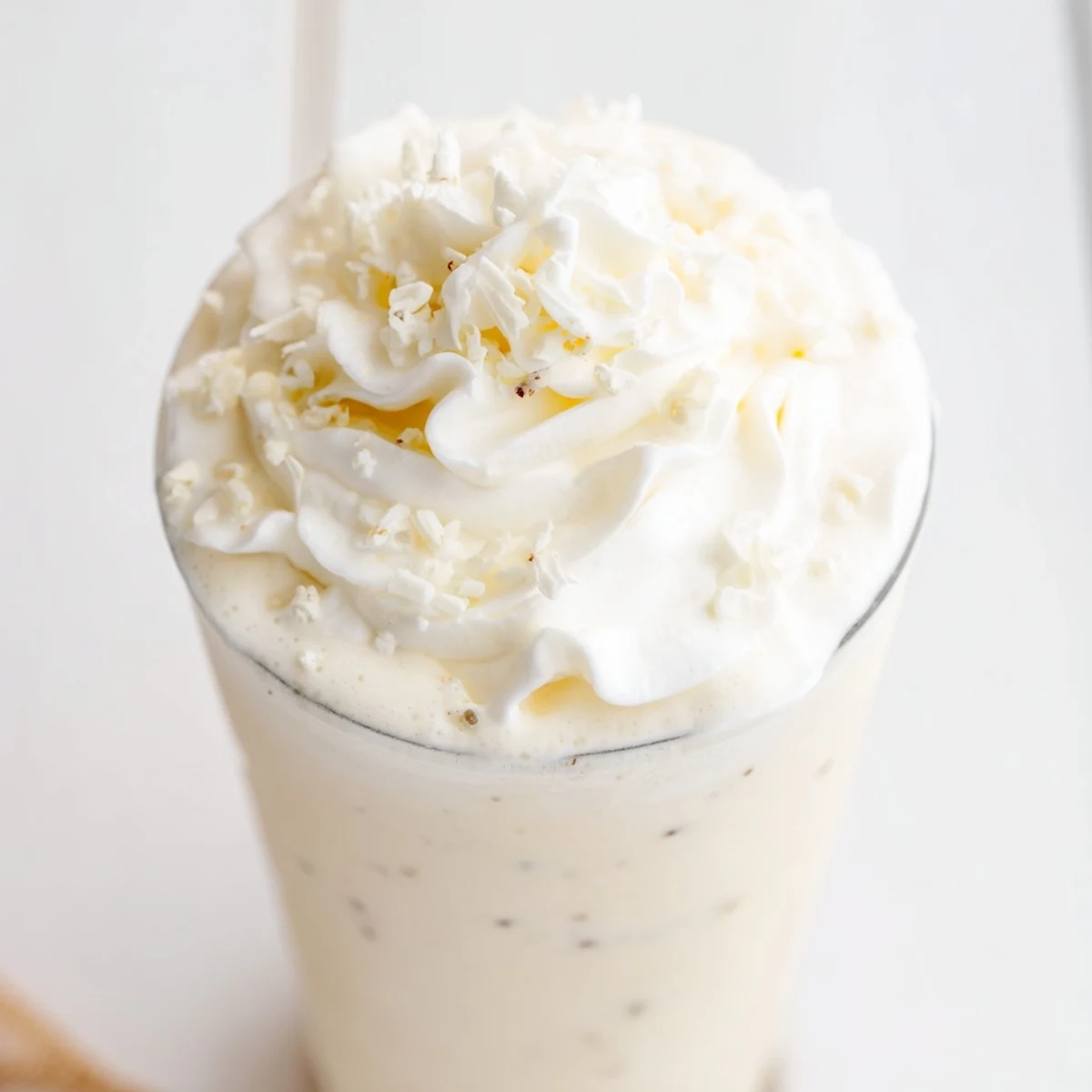 A freshly blended Vanilla Bean Frappuccino being poured into a glass, showing its smooth, frosty texture.