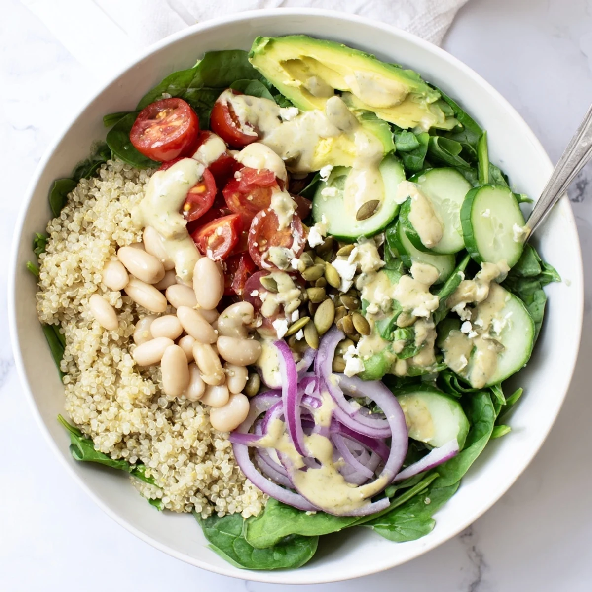 A vibrant Spinach & White Bean Ultimate Protein Power Bowl topped with creamy avocado and crunchy pumpkin seeds.