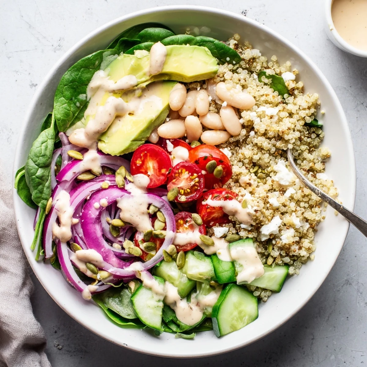 Colorful Spinach & White Bean Ultimate Protein Power Bowl with cherry tomatoes, cucumber, and crumbled feta cheese.