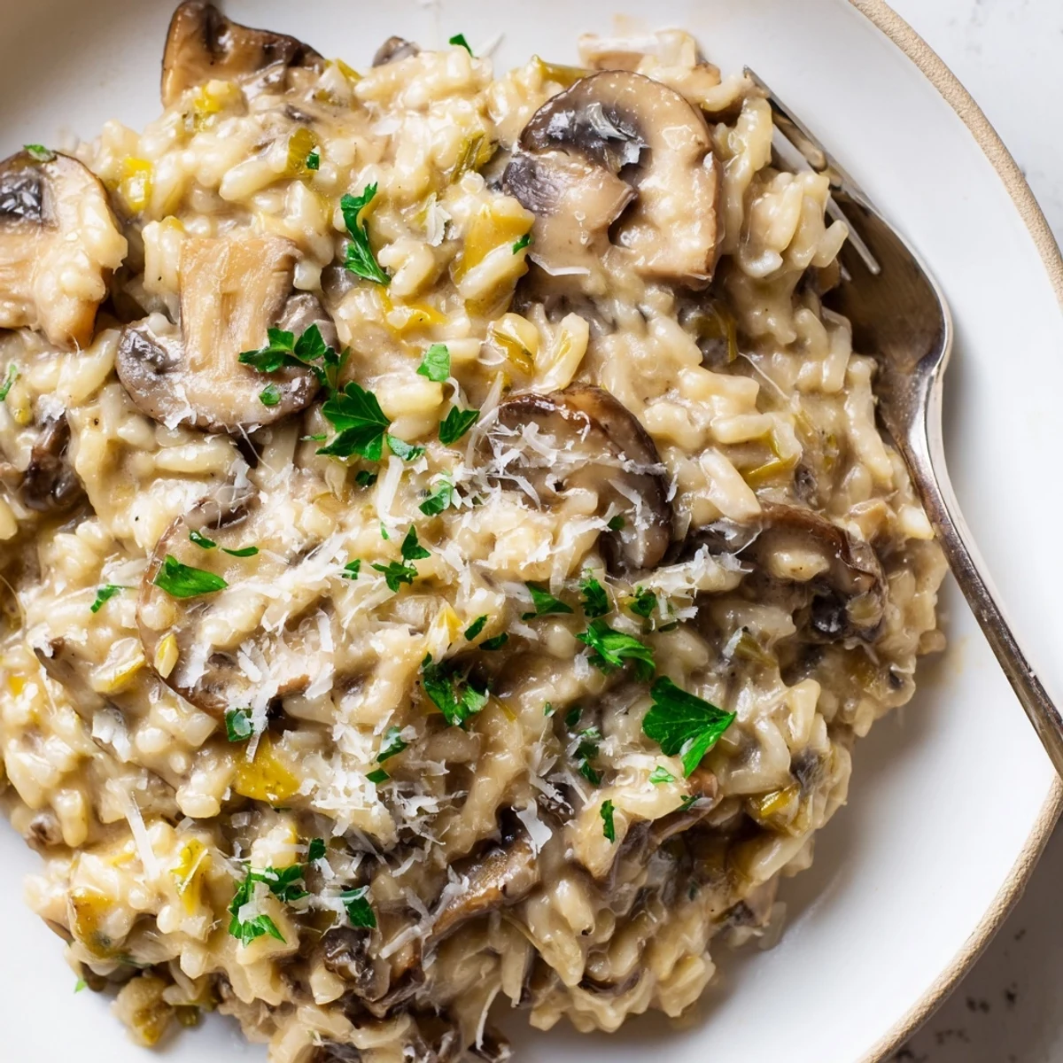 Steaming Creamy Mushroom Risotto served in a shallow dish, with a spoon showing the velvety texture and a glass of white wine nearby.
