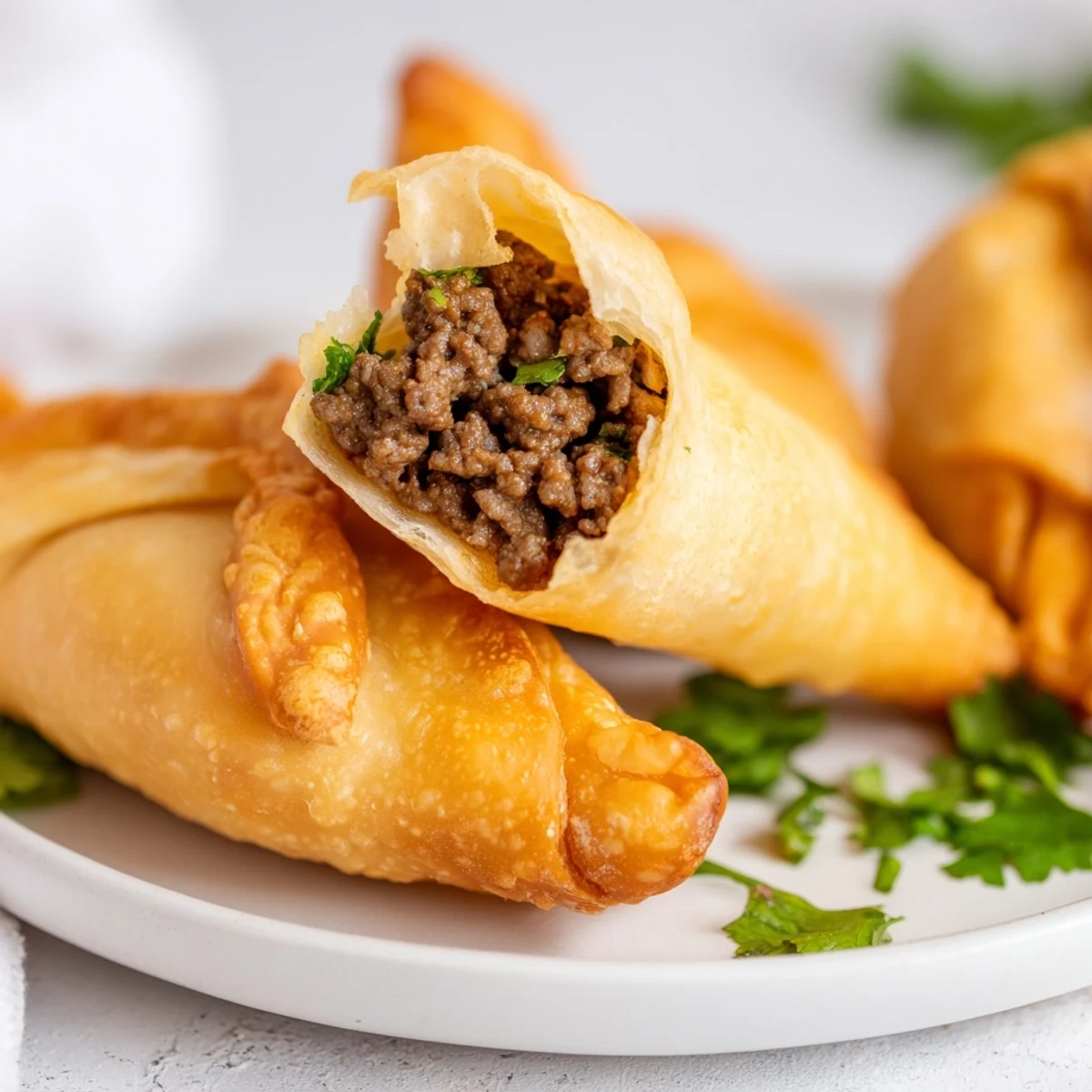 A close-up of a broken Spiced Meat Sambusa revealing savory ground beef and aromatic spices inside.