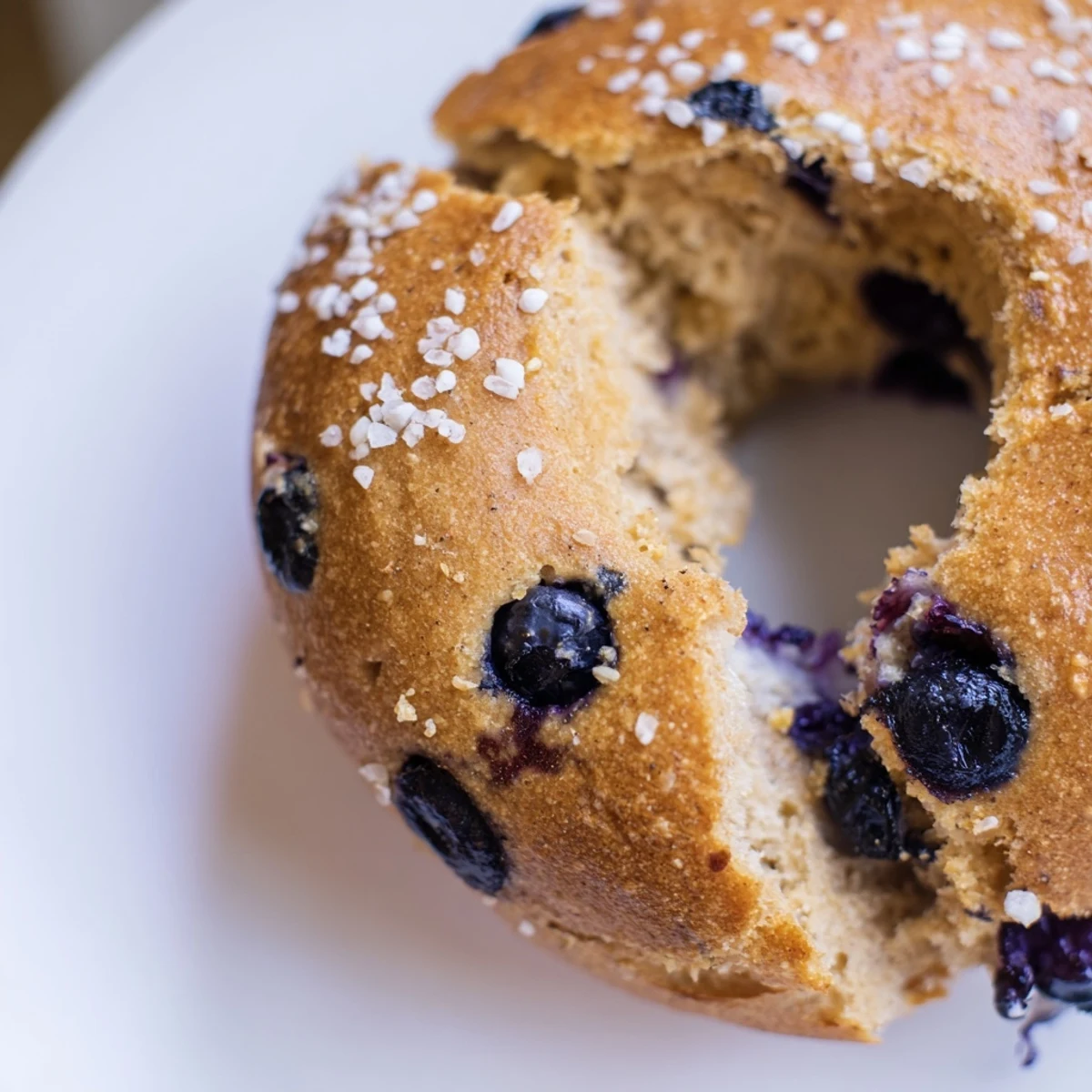 Freshly baked Gluten-Free Blueberry Bagels with a golden crust and juicy blueberries on a wooden board.