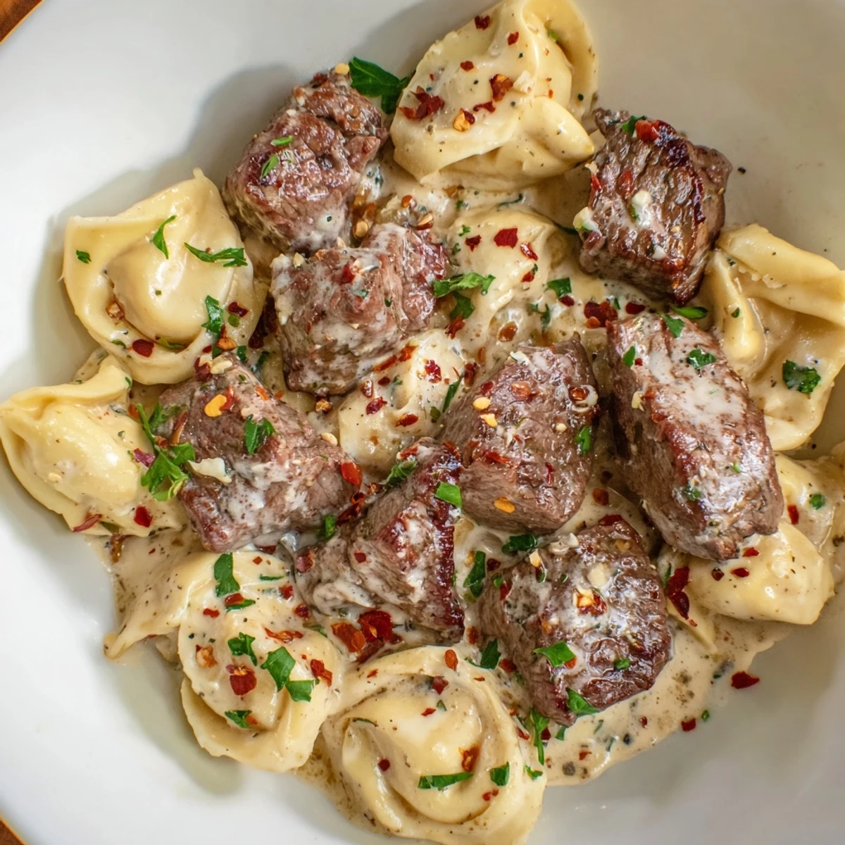 A close-up of garlic steak tortellini featuring juicy steak bites and cheese tortellini in creamy sauce.