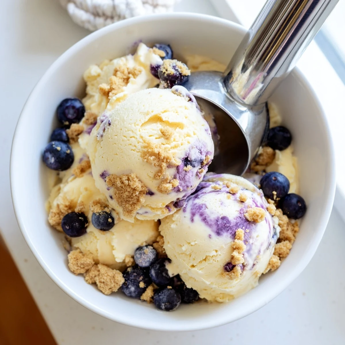 Close-up of creamy Lemon Blueberry Cheesecake Ice Cream showing a purple blueberry swirl and rich cheesecake texture.