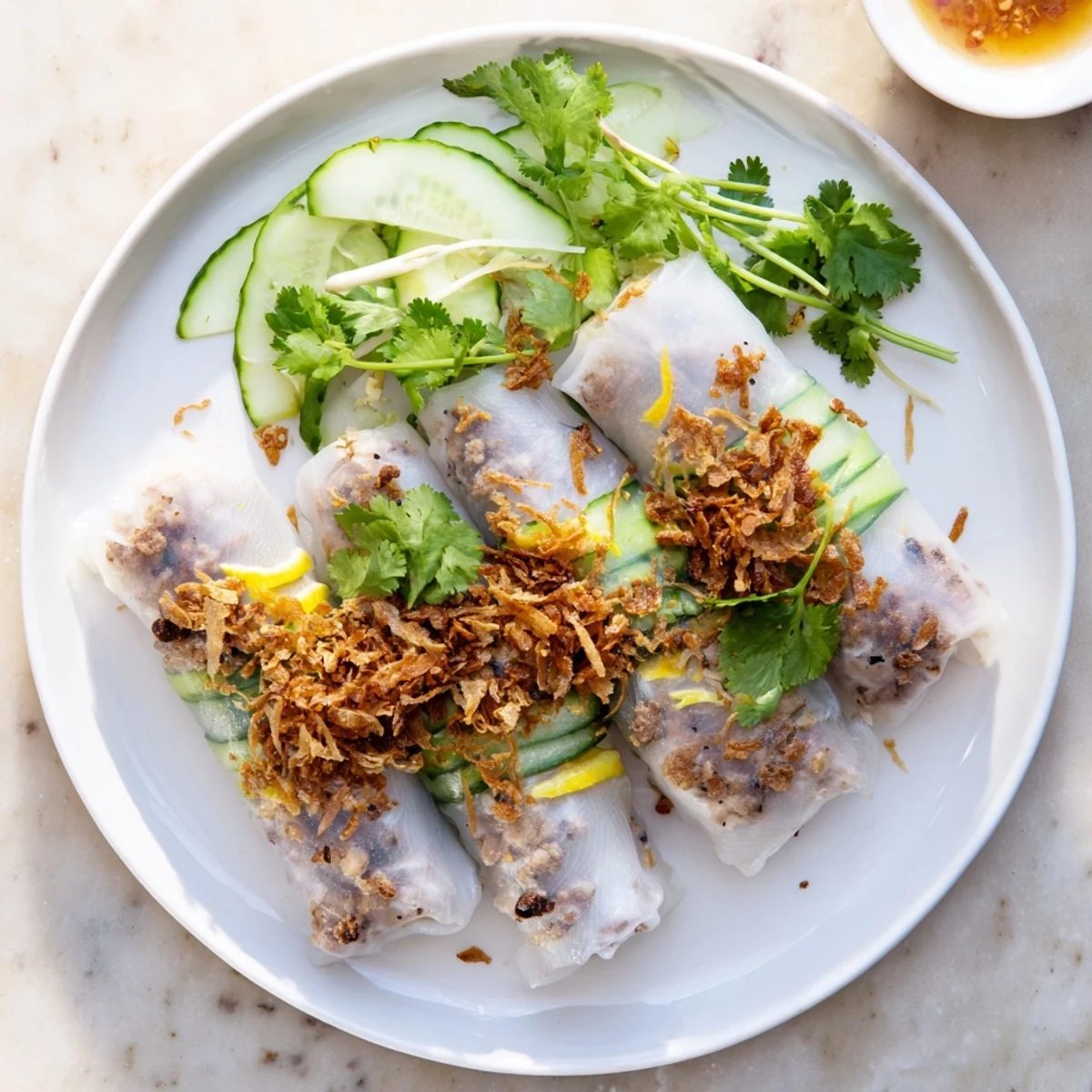 Close-up of soft Banh Cuon rice rolls filled with ground pork and mushrooms, ready to be dipped in a garlicky Vietnamese sauce.