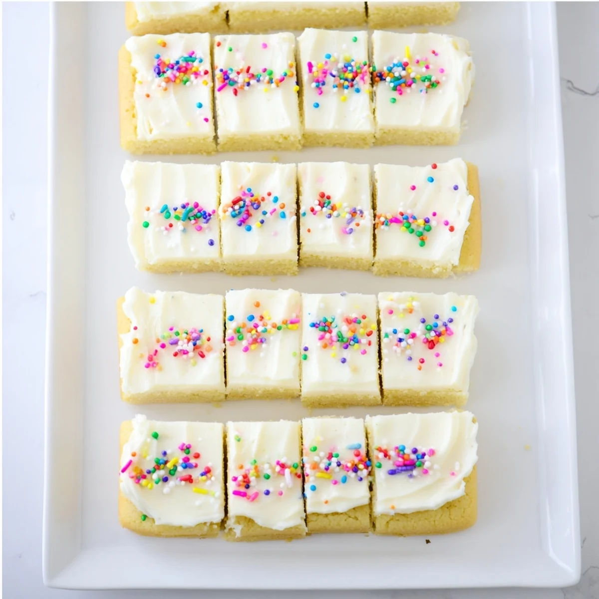Thick sugar cookie bars spread with sweet buttercream frosting and decorated with bright sprinkles for parties and holidays