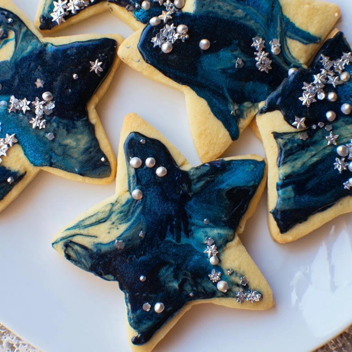 Golden starry night sugar cookies topped with swirled blue icing and sparkling edible stars