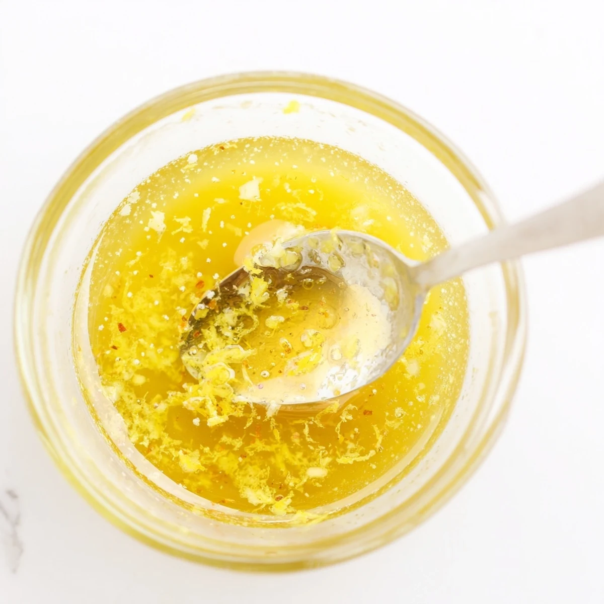 Zesty bright lemon vinaigrette dressing poured generously over crisp garden salad with colorful vegetables