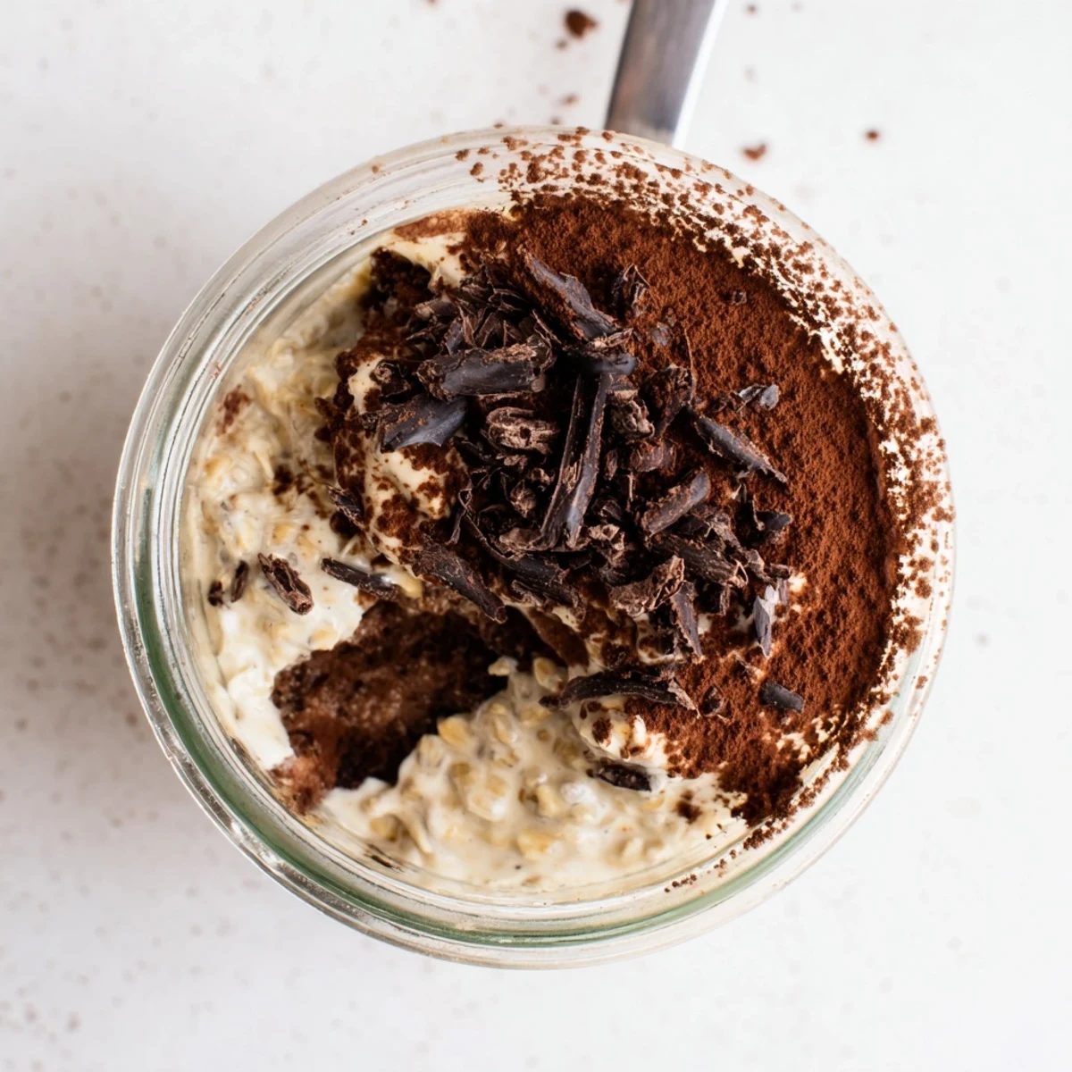Spoon lifting creamy espresso-infused overnight oats inspired by classic Italian tiramisu dessert