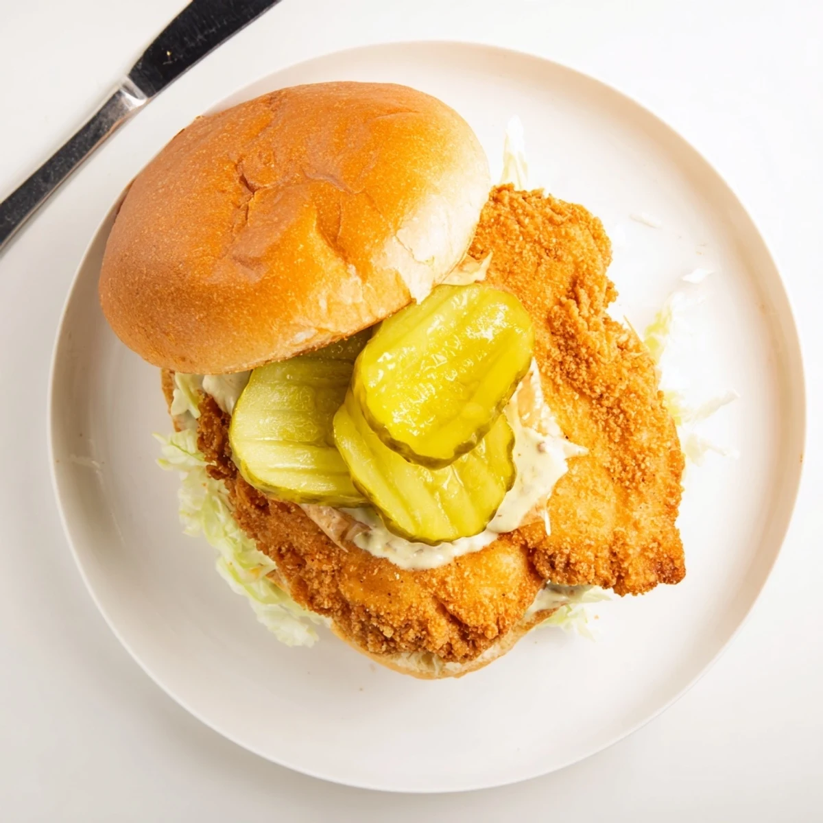 Golden fried crispy chicken burger stacked with fresh lettuce and pickles on toasted brioche bun