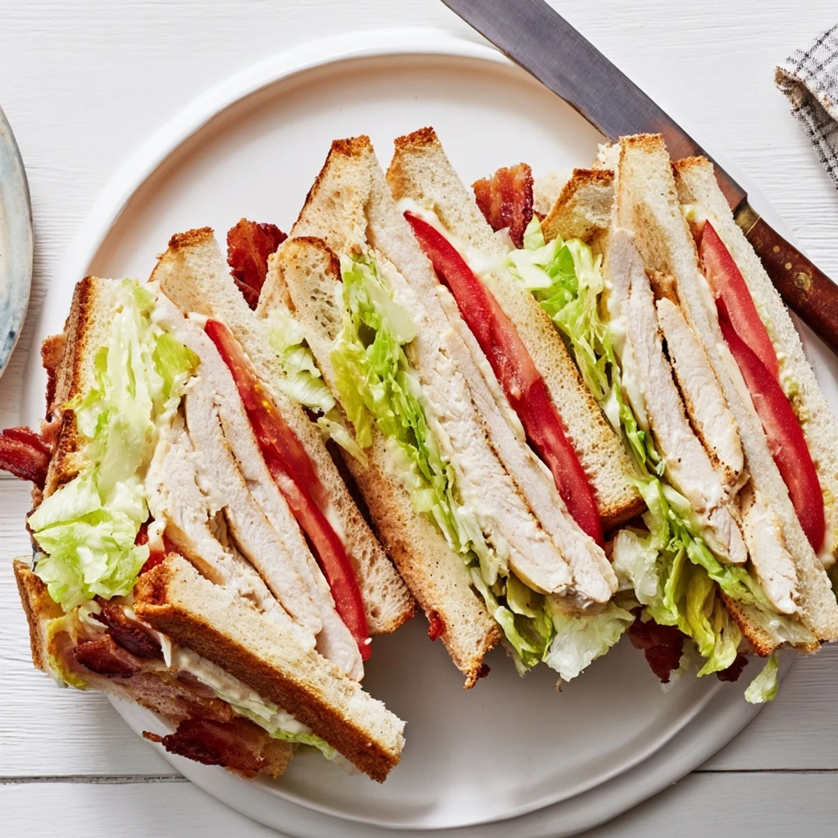 Triple-decker chicken club sandwich layered with crispy bacon, lettuce, tomato, and creamy mayonnaise on toasted bread
