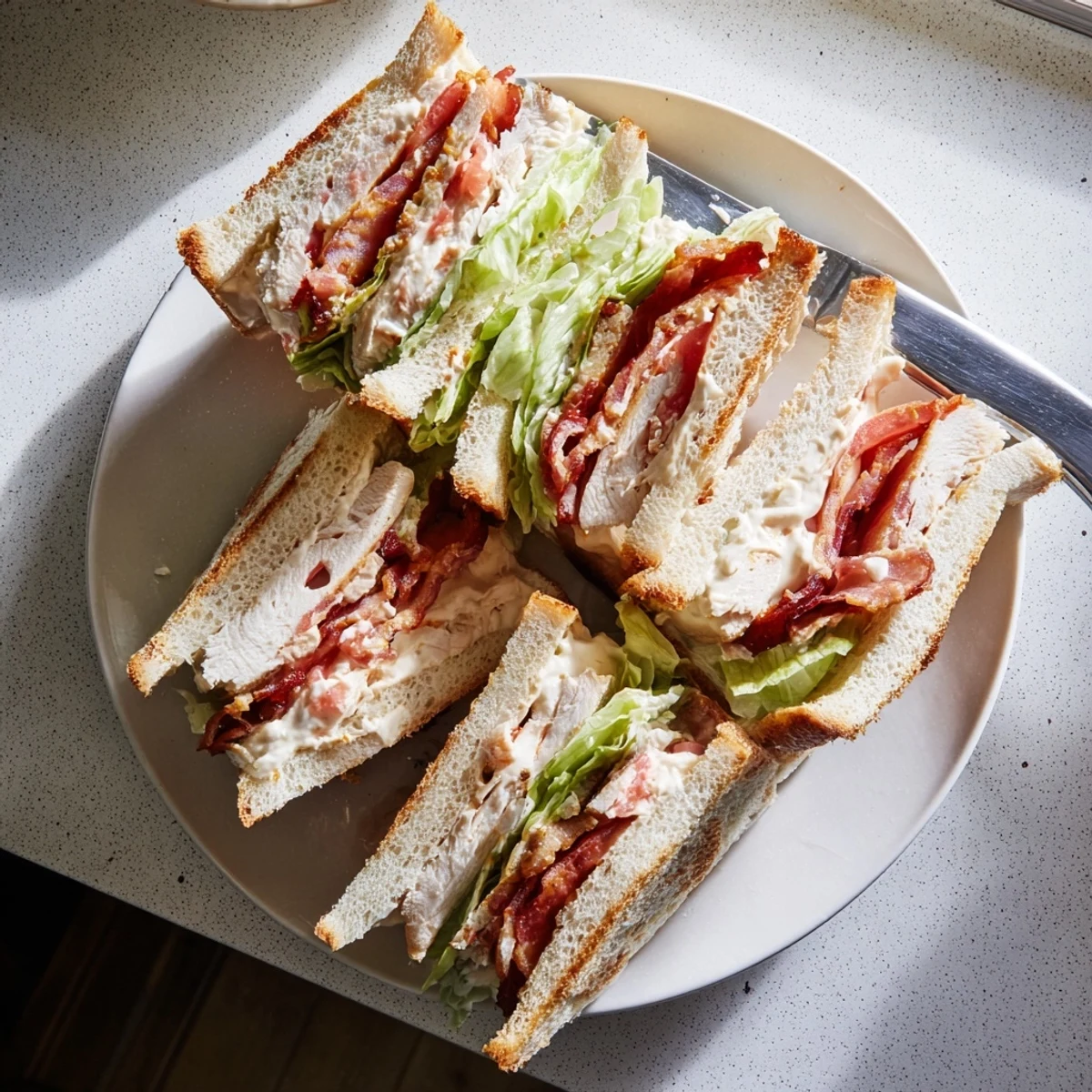 Sliced diagonal chicken club sandwich showcasing juicy chicken, crispy bacon, and fresh vegetables between golden toasted slices