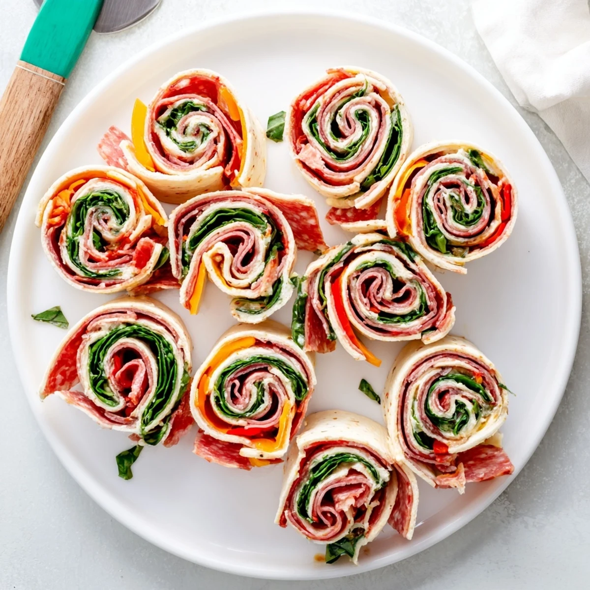 Savory Italian pinwheels arranged on a serving platter with fresh green spinach and herbs visible