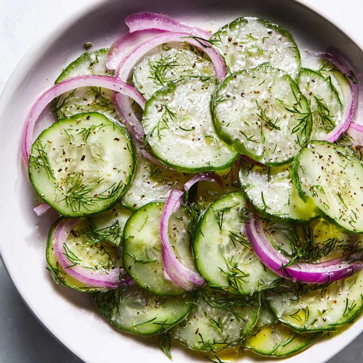 Chilled Easy Refreshing Cucumber Salad tossed with olive oil dressing, garnished with green dill sprigs