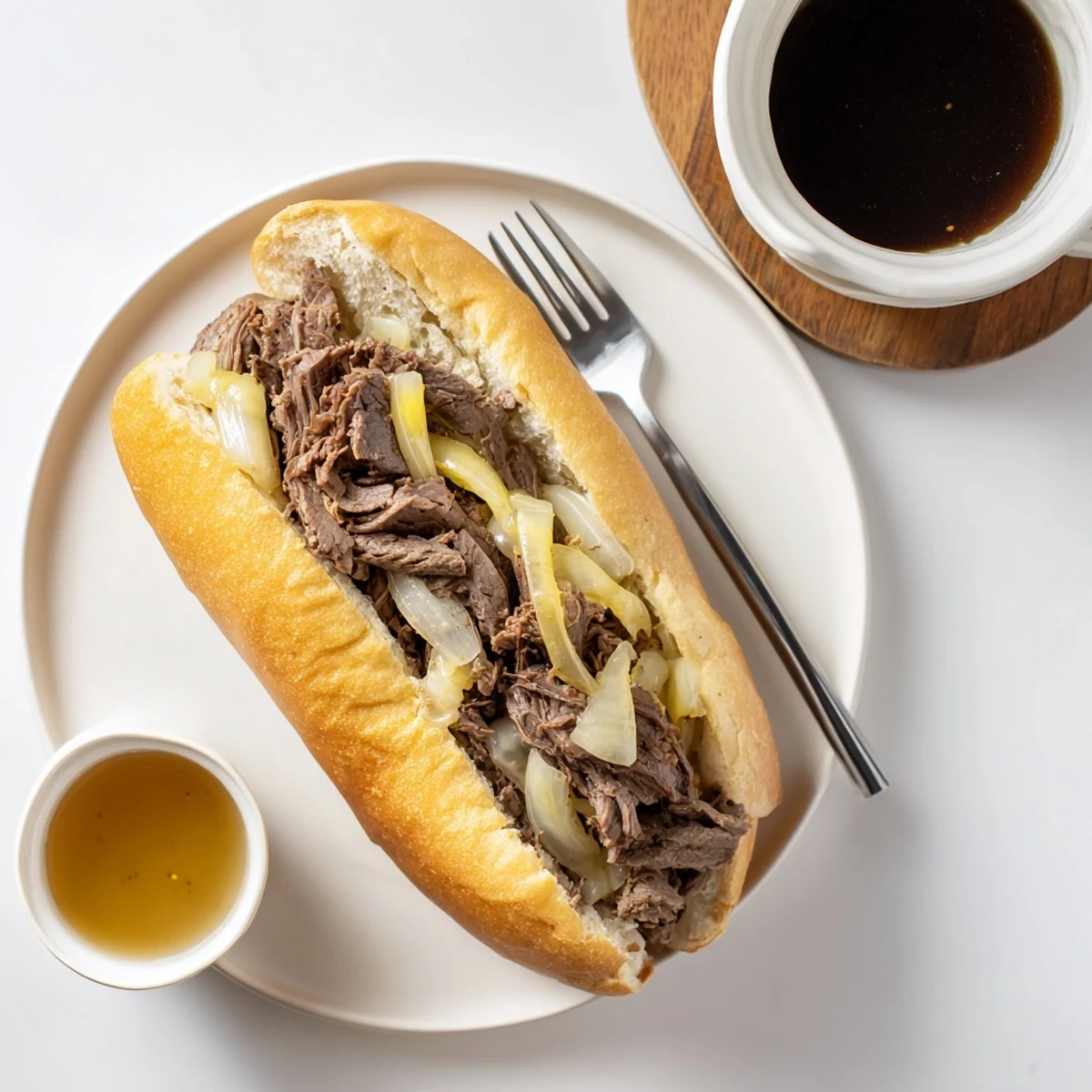 Toasty sandwich filled with juicy beef from Crockpot French Dip Sandwiches served alongside small bowl of rich au jus