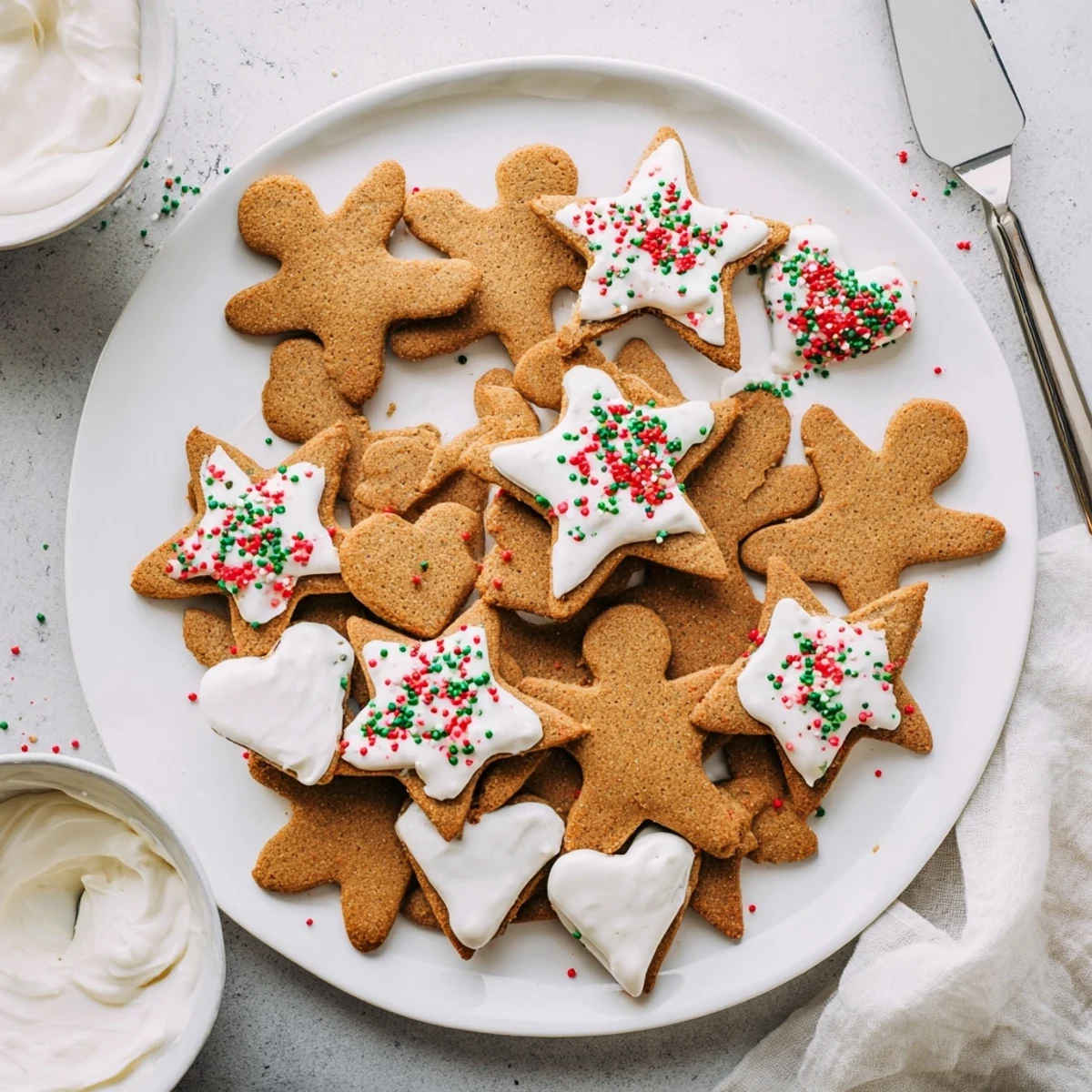 Classic cut out gingerbread cookies decorated with white icing and colorful sprinkles on a wooden cutting board