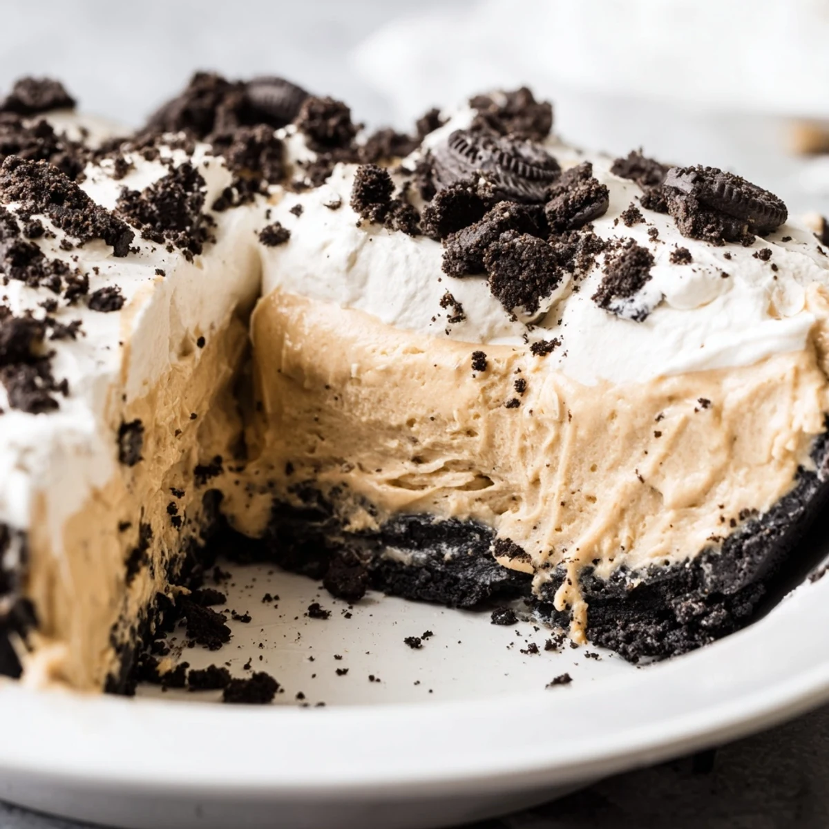 Creamy peanut butter Oreo pie sliced thick with whipped cream and cookie crumbles