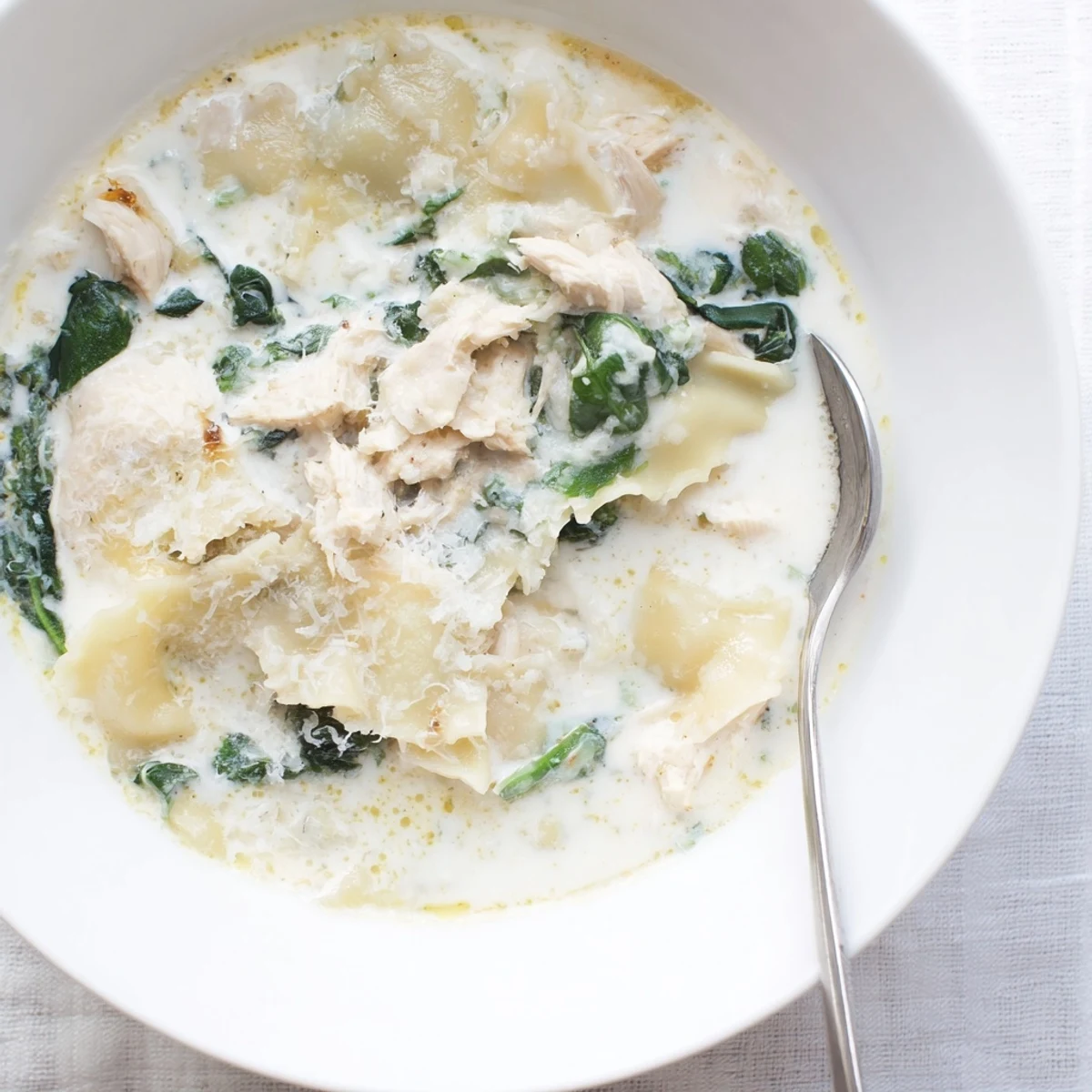 Creamy white lasagna soup in a white bowl with melted cheese and tender noodles