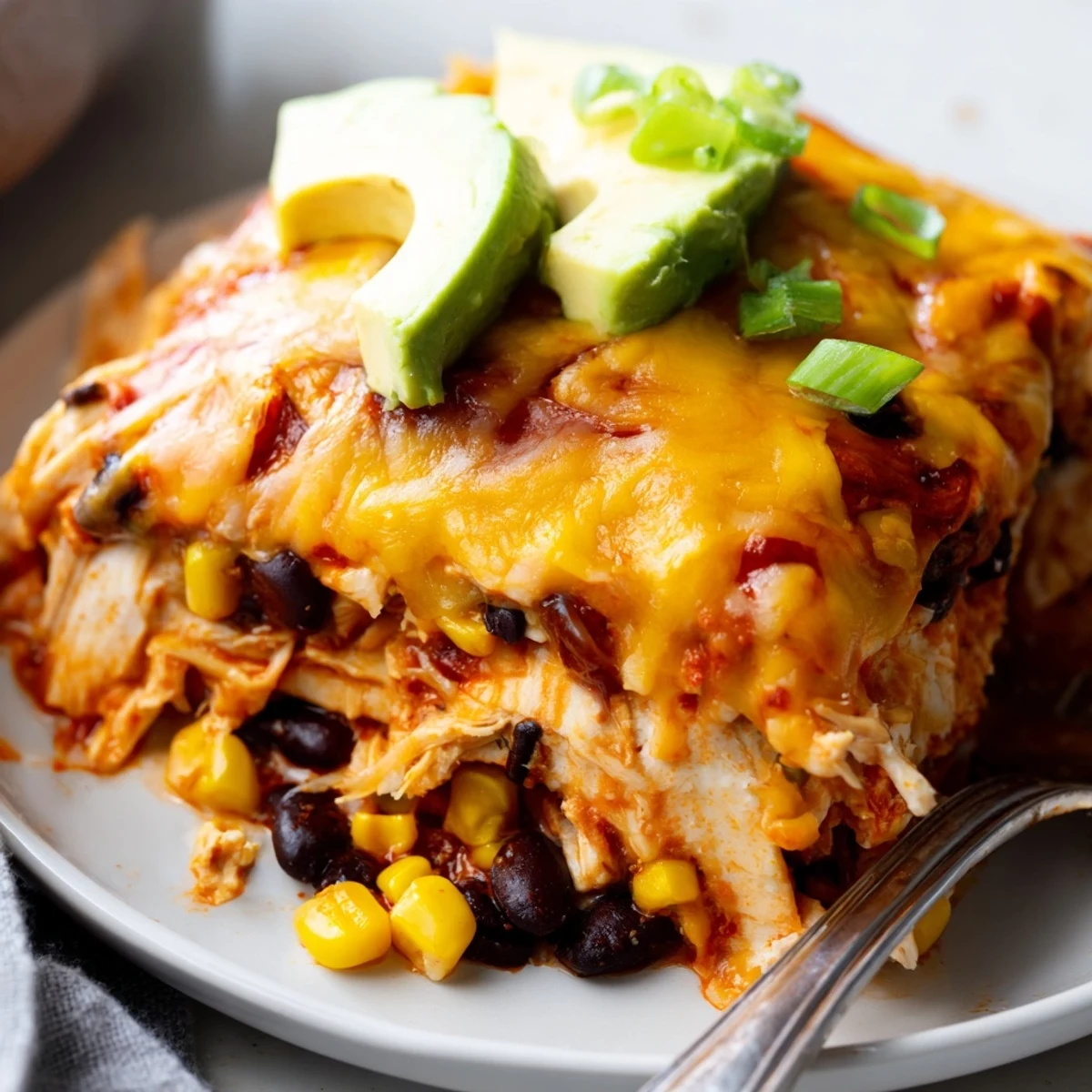 Golden bubbling cheesy shredded chicken enchilada bake topped with black olives and fresh cilantro