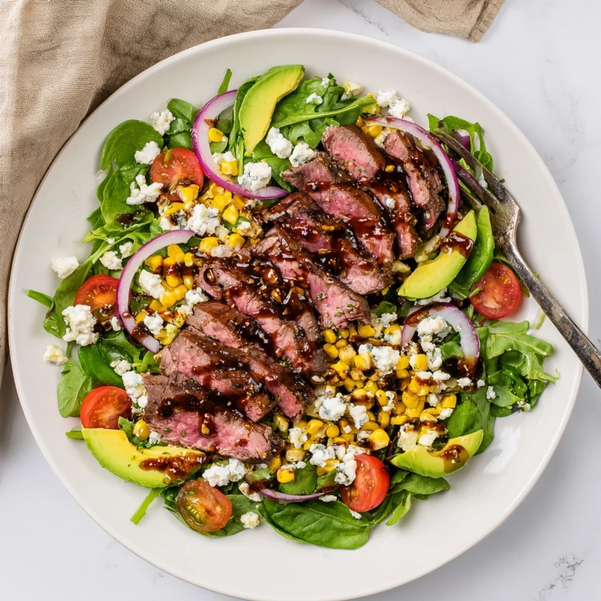 A vibrant balsamic steak gorgonzola salad drizzled with vinaigrette over mixed greens