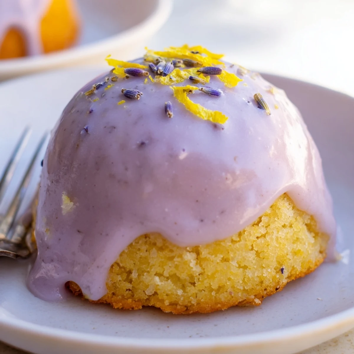 Freshly baked mini lemon cakes with lavender glaze pooling on a wire rack