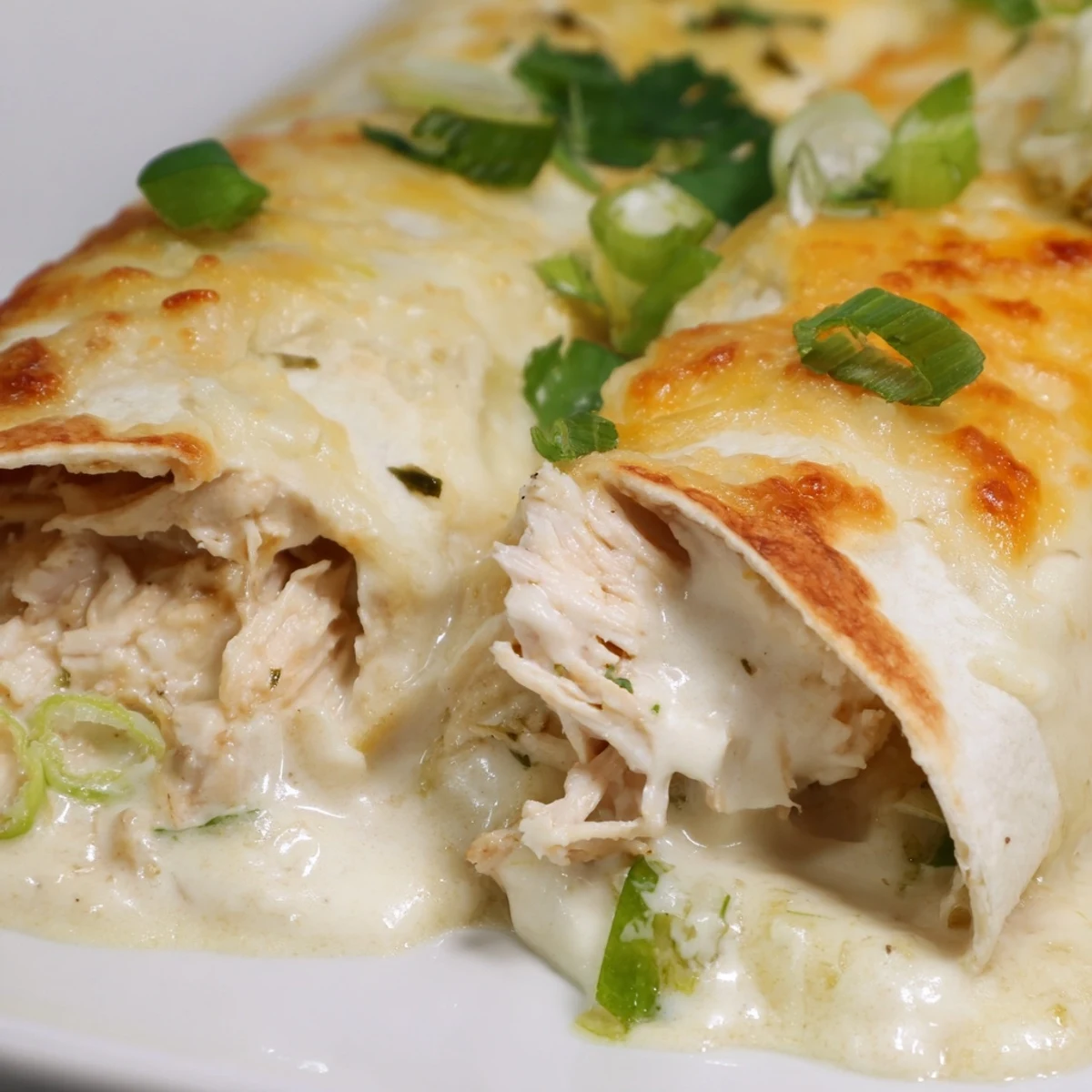 Creamy White Chicken Enchiladas bubbling, velvety sauce and golden cheese topping