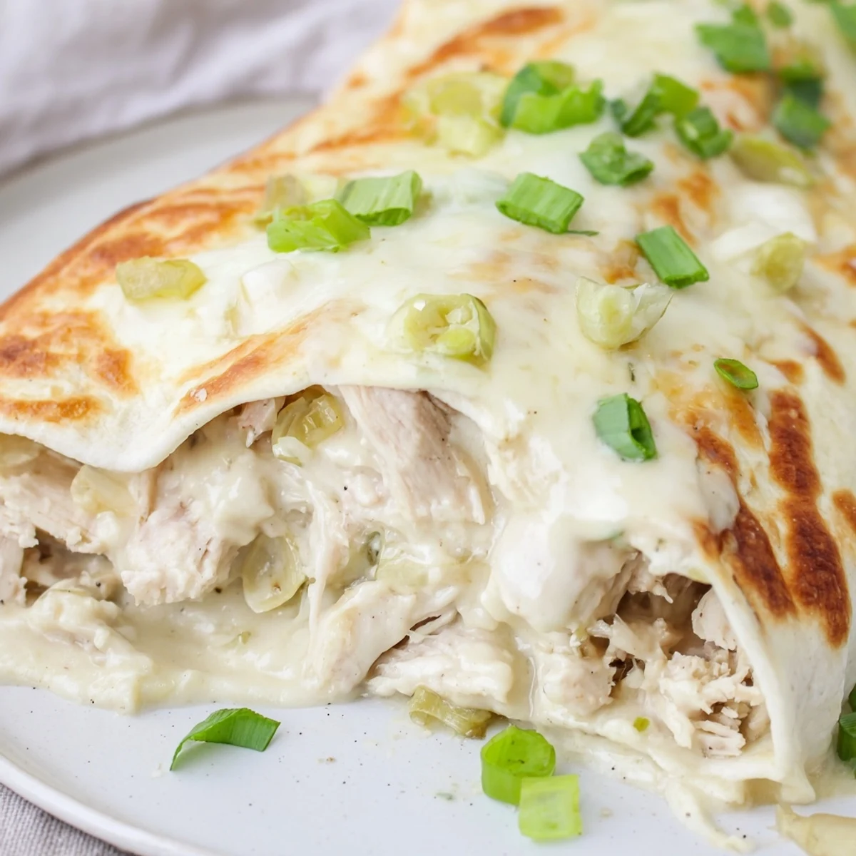 A slice of Creamy White Chicken Enchiladas beside Spanish rice, steam rising