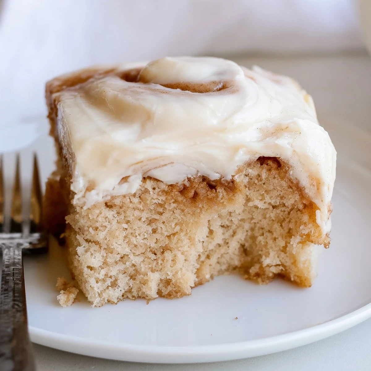 Warm Cinnamon Roll Poke Cake topped with creamy frosting and cinnamon swirls