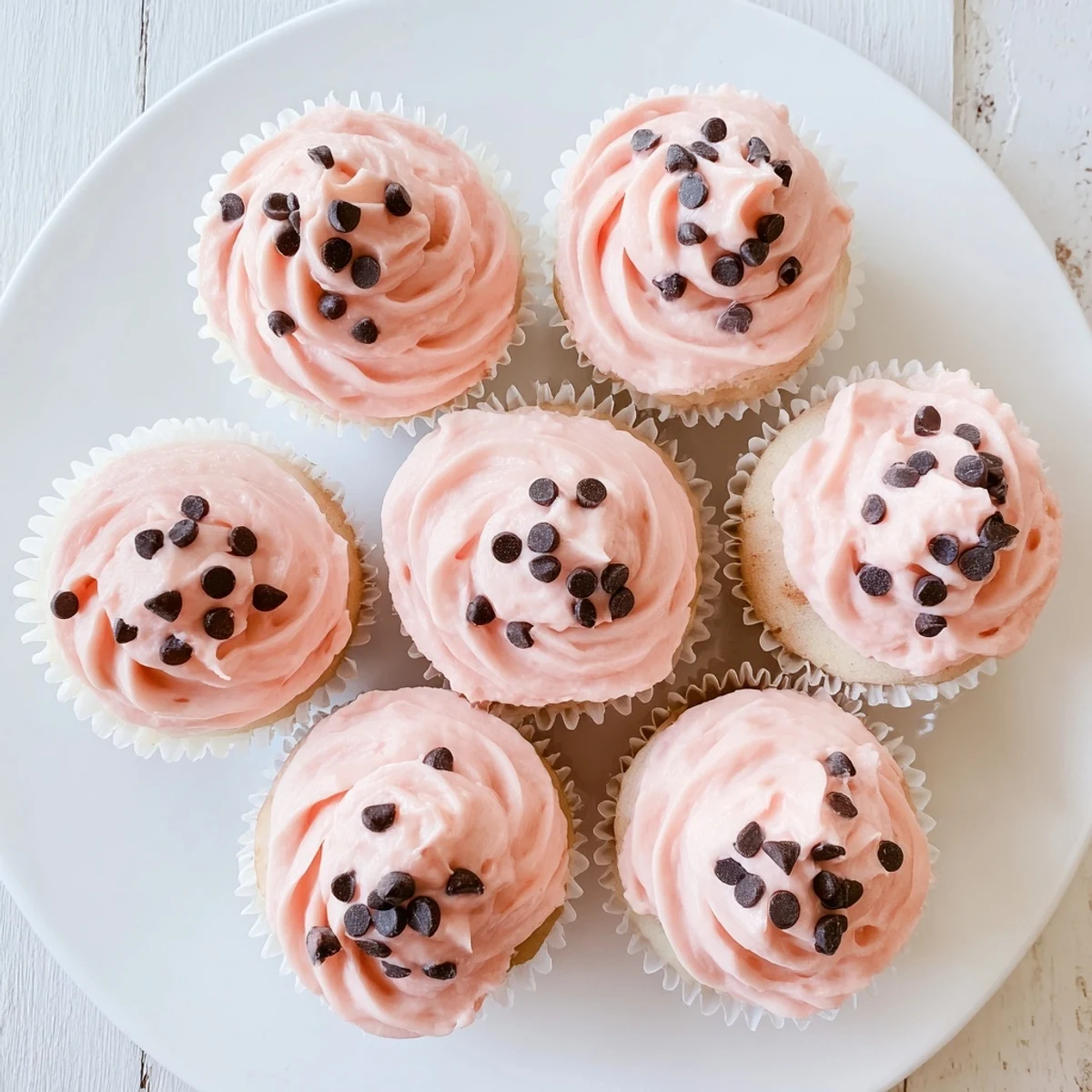 Moist watermelon cupcakes topped with creamy pink frosting and mini chocolate chip seeds