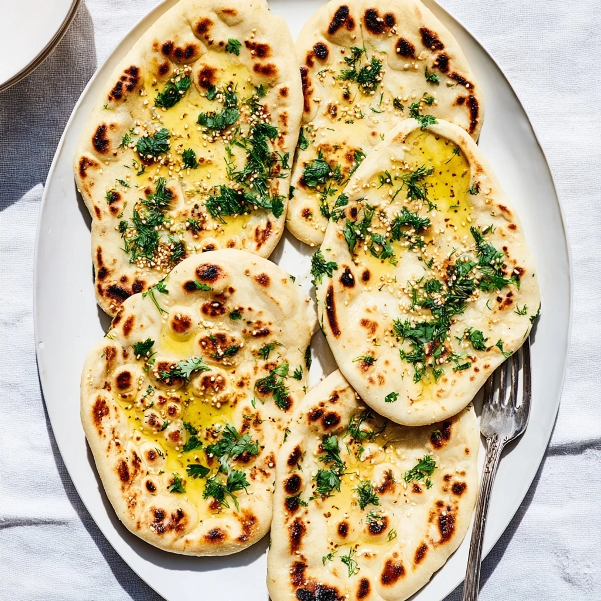 Stack of warm, pillowy sourdough discard soft naan with golden charred spots