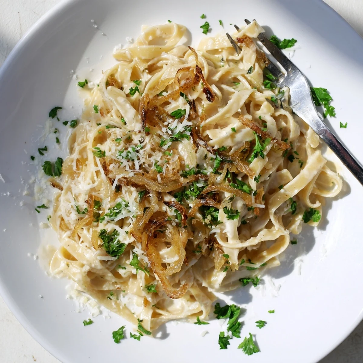 Creamy fettuccine tossed with deeply caramelized onions and rich parmesan sauce served in white bowl