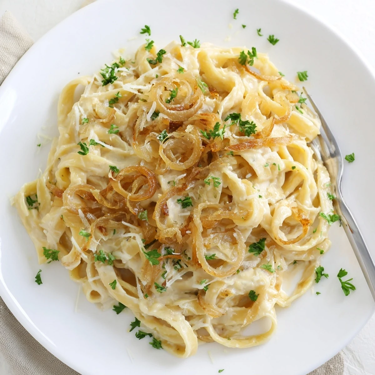 Plate of caramelized onion cream pasta featuring tender noodles enveloped in velvety white sauce and herbs