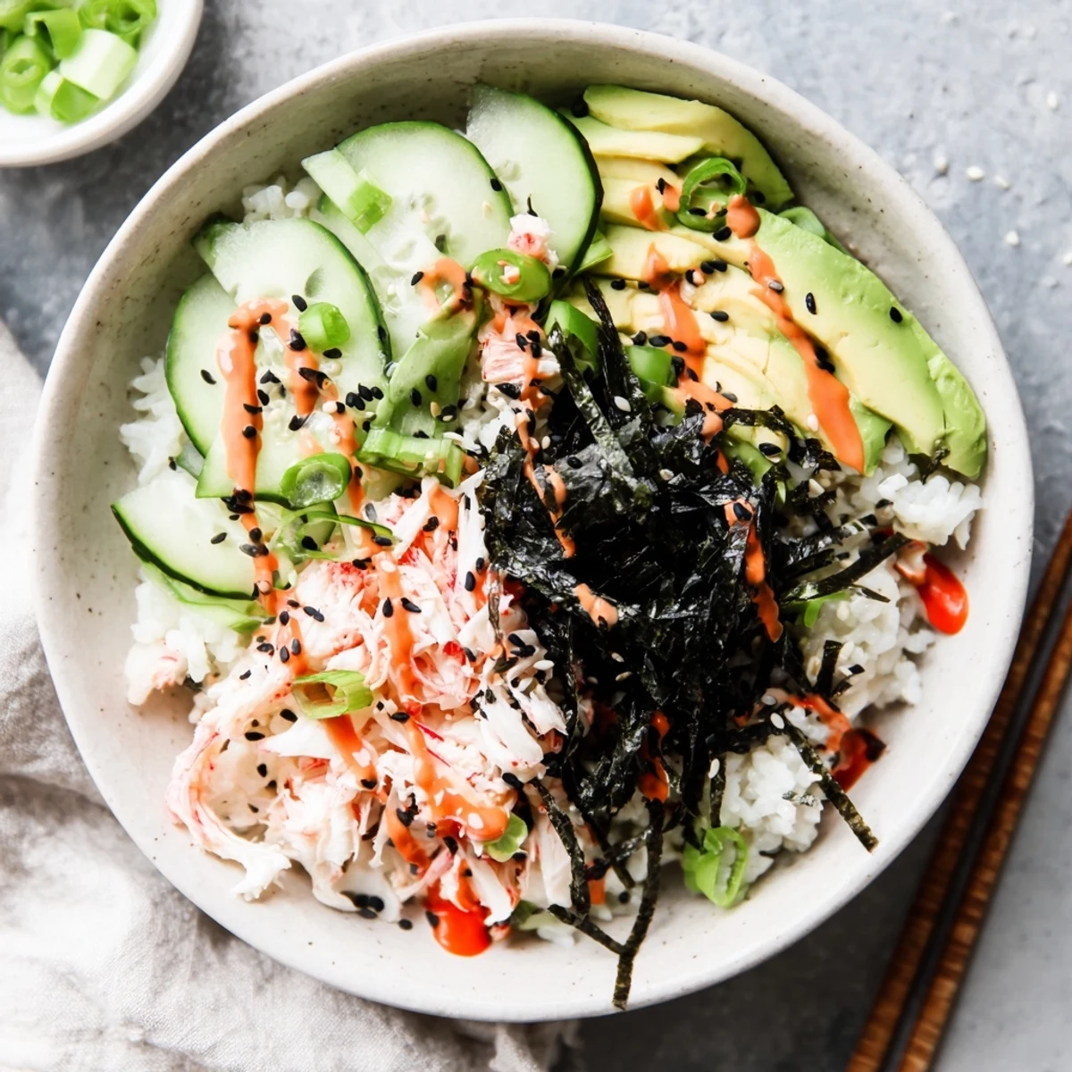 Colorful California roll bowl arrangement with shredded crab, diced avocado, pickled ginger and toasted sesame seeds