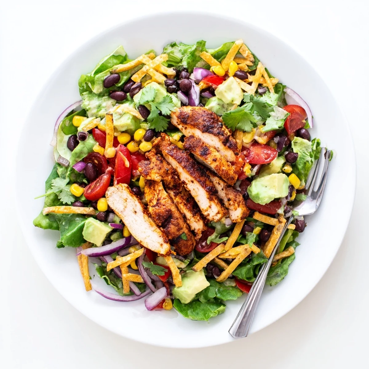 Fresh Southwestern chicken salad topped with warm grilled chicken slices, avocado, colorful vegetables, and zesty lime dressing